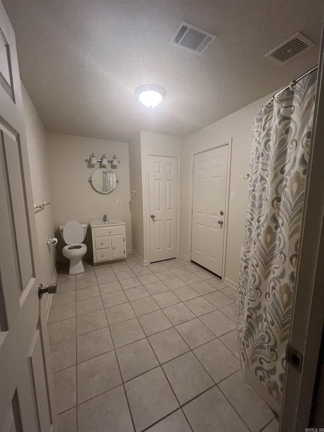 bathroom with vanity, a textured ceiling, tile patterned floors, and toilet