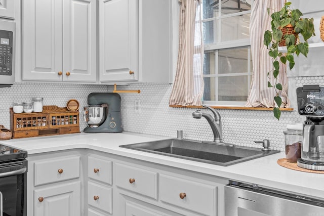 kitchen with black electric range oven, sink, stainless steel dishwasher, decorative backsplash, and white cabinetry