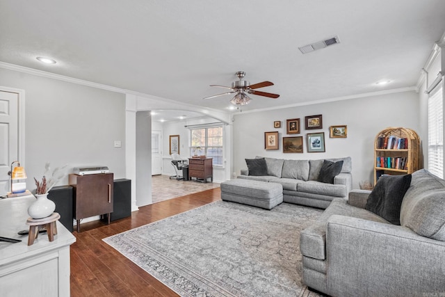 living room featuring decorative columns, crown molding, ceiling fan, and dark wood-type flooring