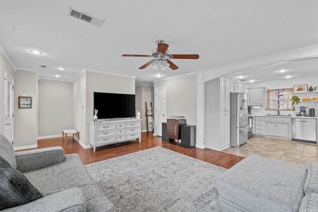 living room featuring light hardwood / wood-style flooring, ceiling fan, crown molding, and sink