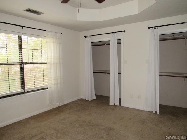 unfurnished bedroom with carpet flooring, multiple windows, and ceiling fan