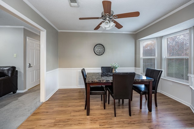 dining space featuring a textured ceiling, light hardwood / wood-style floors, ceiling fan, and ornamental molding