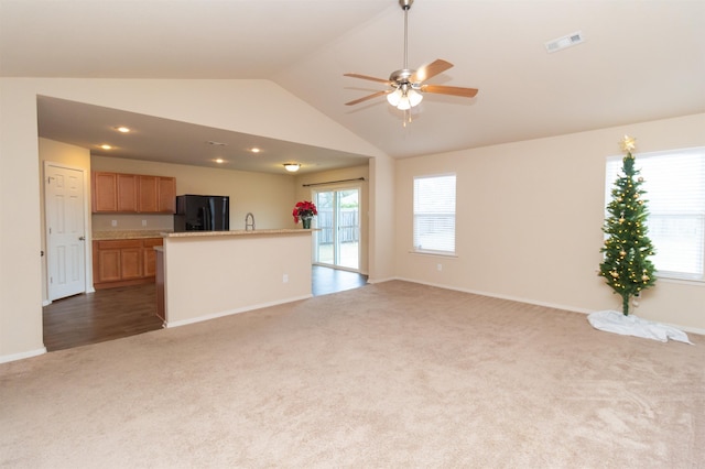 unfurnished living room featuring ceiling fan, sink, lofted ceiling, and dark colored carpet