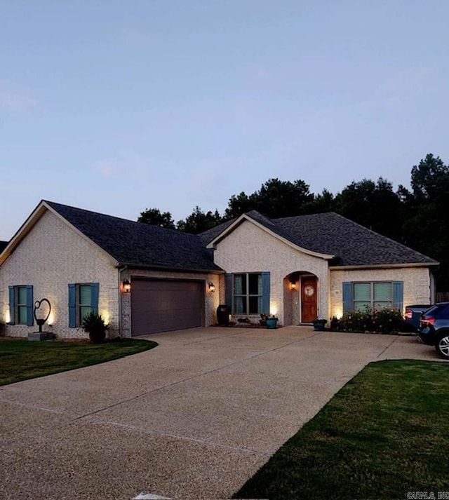 ranch-style home featuring a lawn and a garage