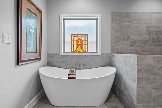 bathroom featuring tile patterned floors, a bath, and tile walls