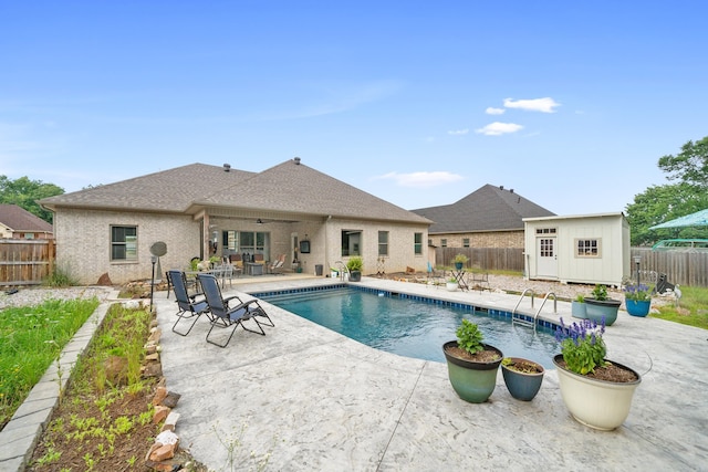 view of swimming pool with a patio, ceiling fan, and a storage shed