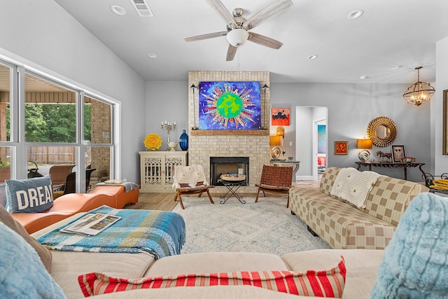 living room featuring hardwood / wood-style flooring, ceiling fan with notable chandelier, and a fireplace