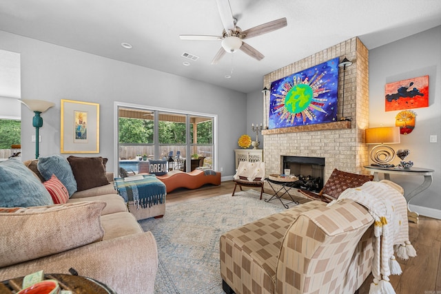 living room with ceiling fan, wood-type flooring, and a brick fireplace