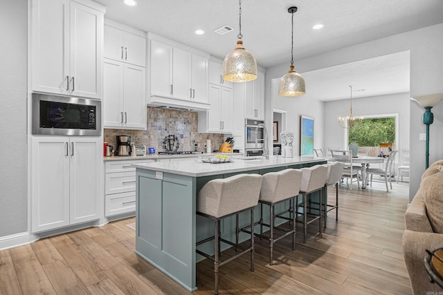 kitchen with white cabinets, appliances with stainless steel finishes, and a center island with sink