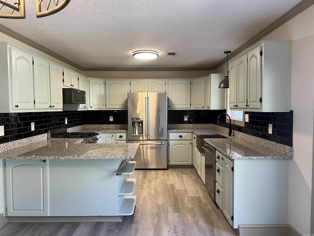 kitchen with stone counters, stainless steel appliances, a textured ceiling, and light hardwood / wood-style floors