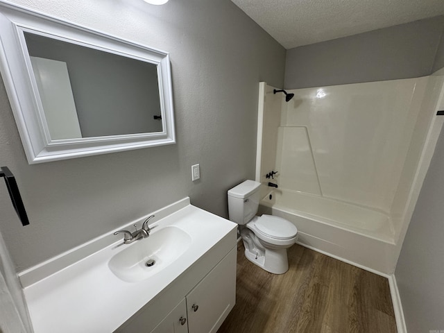 full bathroom featuring hardwood / wood-style floors, vanity, washtub / shower combination, toilet, and a textured ceiling