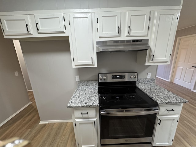 kitchen with electric range, white cabinetry, extractor fan, and light stone counters