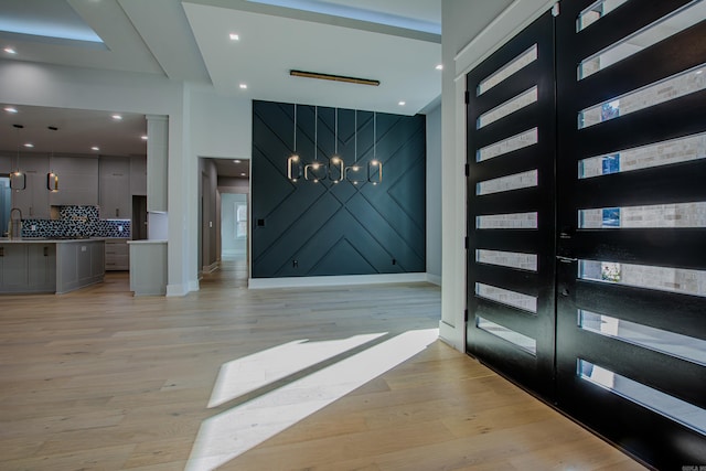 entrance foyer with french doors, a chandelier, and light hardwood / wood-style flooring