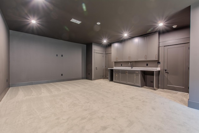 basement featuring sink and light colored carpet