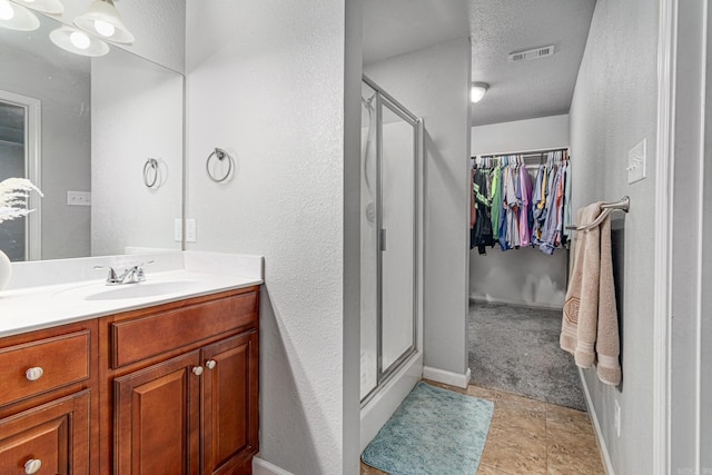 bathroom with tile patterned floors, a shower with door, vanity, and a textured ceiling