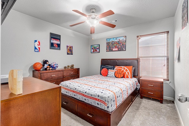 carpeted bedroom with ceiling fan and a textured ceiling