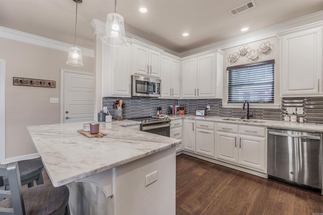 kitchen featuring a kitchen breakfast bar, stainless steel appliances, white cabinetry, and sink