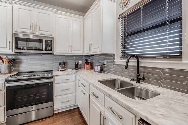 kitchen with appliances with stainless steel finishes, backsplash, dark hardwood / wood-style flooring, sink, and white cabinetry