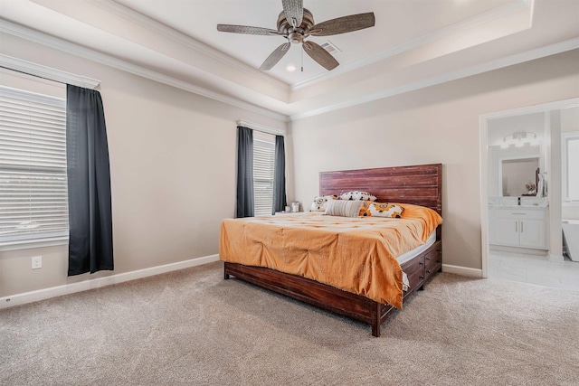 carpeted bedroom featuring ensuite bathroom, ornamental molding, a raised ceiling, ceiling fan, and multiple windows