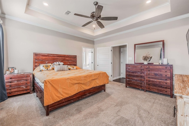 carpeted bedroom featuring a raised ceiling, ceiling fan, crown molding, and ensuite bathroom