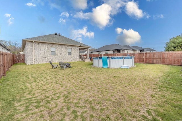 rear view of property with a fenced in pool and a yard