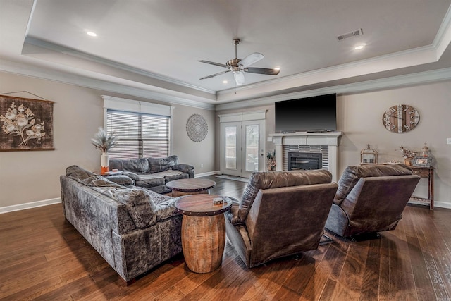 living room featuring a tray ceiling, crown molding, ceiling fan, and dark hardwood / wood-style floors