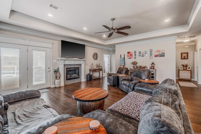 living room featuring ornamental molding, a tray ceiling, ceiling fan, and dark wood-type flooring