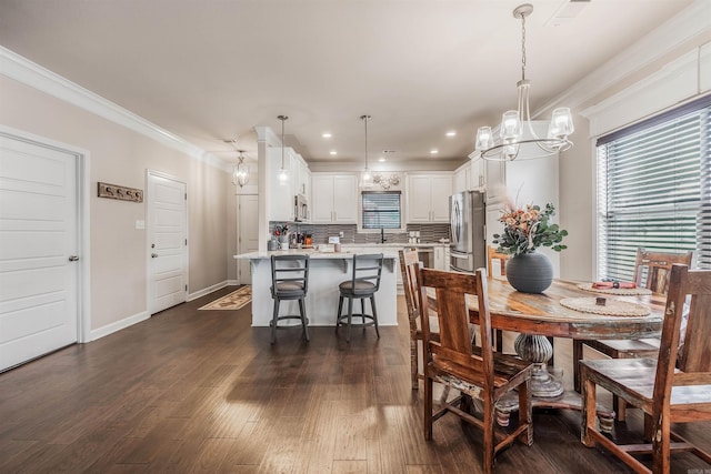 dining room featuring dark hardwood / wood-style floors, ornamental molding, sink, and an inviting chandelier