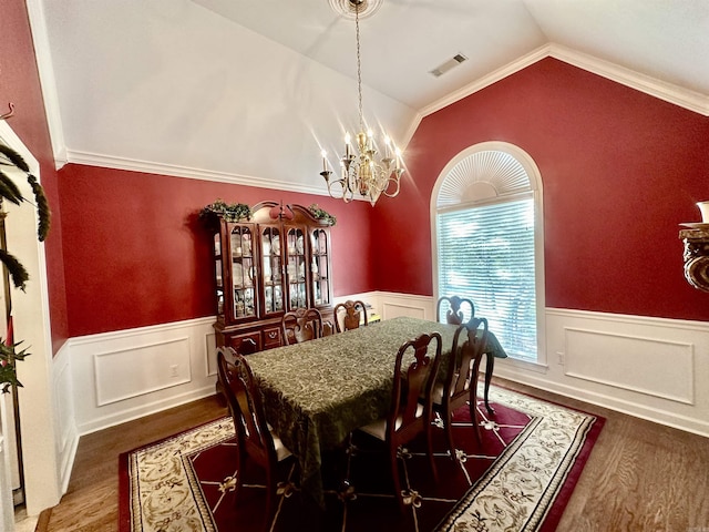 dining space with a chandelier, hardwood / wood-style floors, crown molding, and lofted ceiling