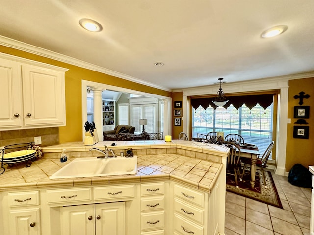 kitchen featuring kitchen peninsula, tile countertops, crown molding, and sink