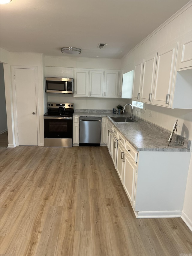 kitchen with sink, white cabinets, light hardwood / wood-style floors, and appliances with stainless steel finishes