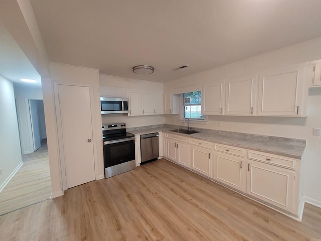 kitchen featuring white cabinets, appliances with stainless steel finishes, light hardwood / wood-style flooring, and sink