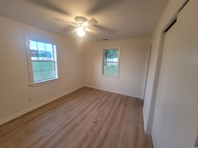 spare room with ceiling fan, a healthy amount of sunlight, and light hardwood / wood-style floors