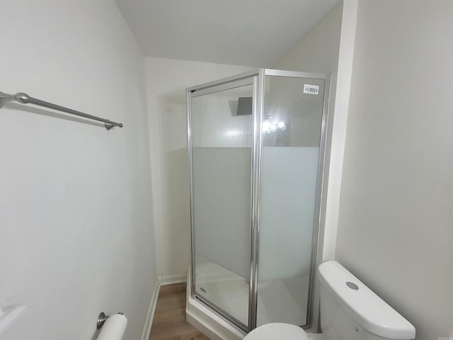 bathroom featuring hardwood / wood-style flooring, toilet, and a shower with shower door