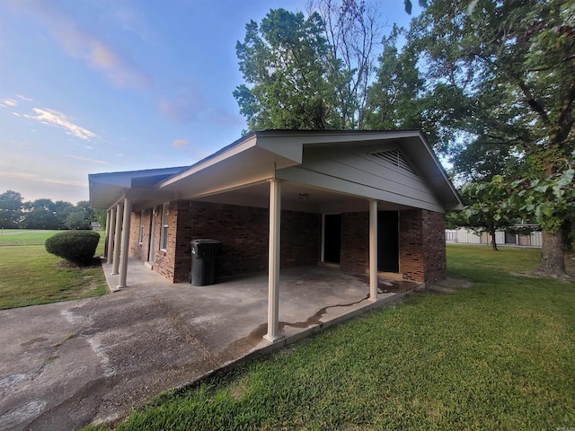 property exterior at dusk featuring a patio area and a lawn