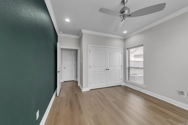 unfurnished bedroom with ceiling fan, light wood-type flooring, crown molding, and a closet