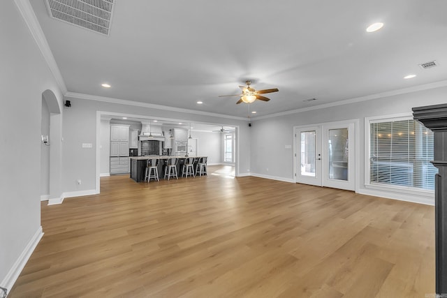 unfurnished living room featuring ceiling fan, light hardwood / wood-style floors, and ornamental molding