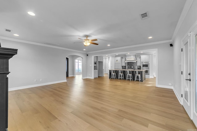 unfurnished living room featuring ceiling fan, crown molding, and light hardwood / wood-style flooring