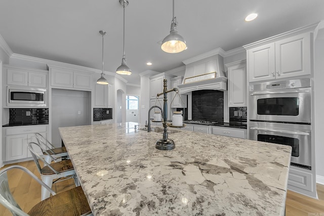 kitchen with decorative backsplash, stainless steel appliances, a spacious island, sink, and decorative light fixtures