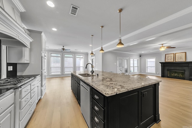 kitchen featuring ceiling fan, sink, white cabinetry, and an island with sink