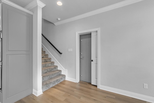 stairs featuring hardwood / wood-style floors and crown molding