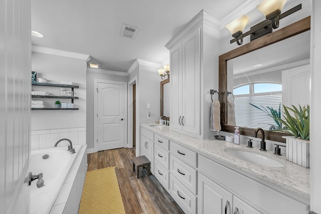 bathroom featuring tiled bath, crown molding, vanity, and hardwood / wood-style flooring