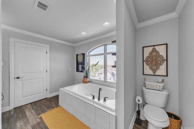 bathroom with hardwood / wood-style flooring, toilet, ornamental molding, and tiled bath