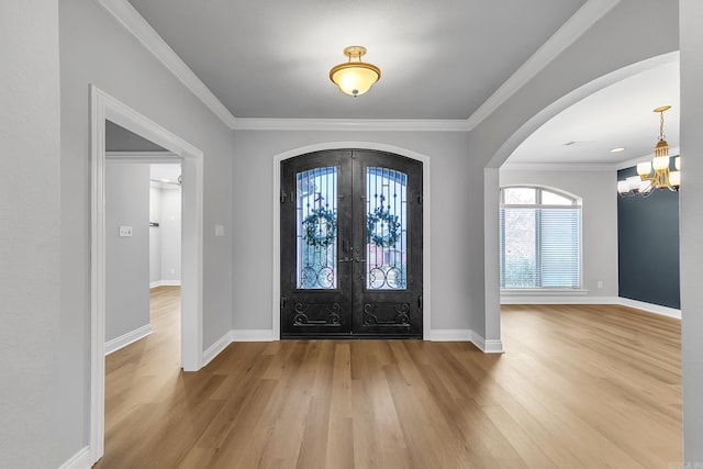 foyer with french doors, an inviting chandelier, hardwood / wood-style floors, and ornamental molding