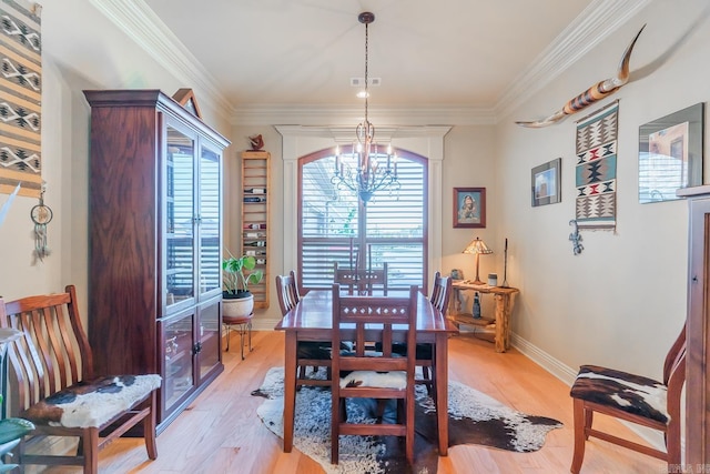 dining area with a chandelier, light hardwood / wood-style floors, and crown molding