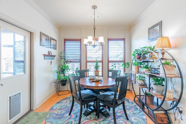 dining room featuring a healthy amount of sunlight, light hardwood / wood-style floors, ornamental molding, and a chandelier