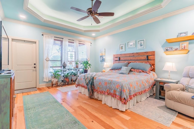 bedroom with hardwood / wood-style floors, a raised ceiling, ceiling fan, and ornamental molding