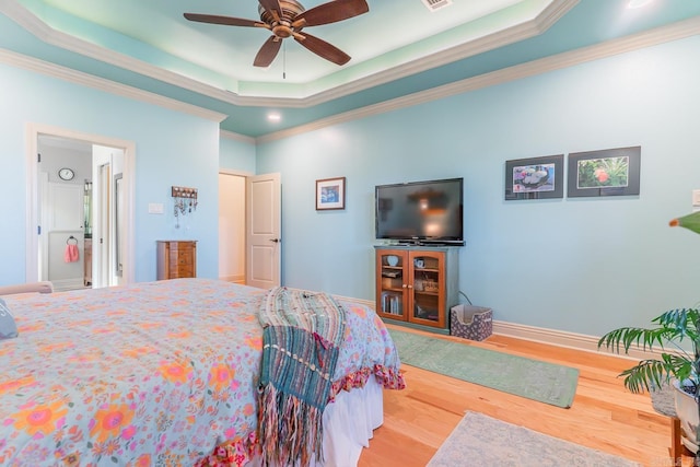 bedroom with hardwood / wood-style floors, a tray ceiling, ceiling fan, and ensuite bathroom