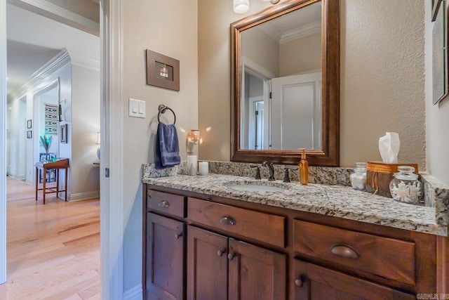 bathroom with crown molding, vanity, and wood-type flooring