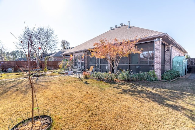 rear view of property with a lawn and a sunroom